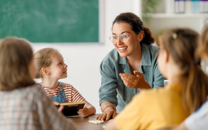 A teacher is talking to a group of children in a classroom.